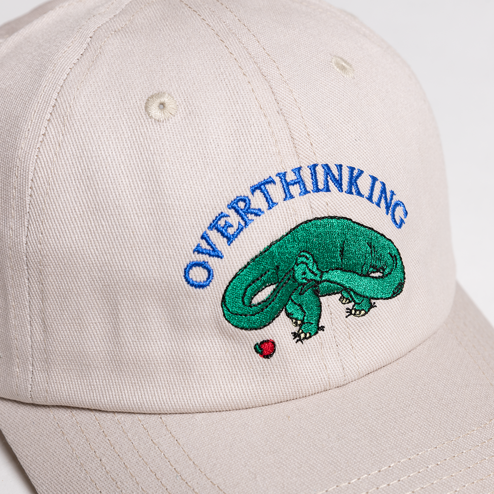 Beige cap with 'OVERTHINKING' and snake graphic design.