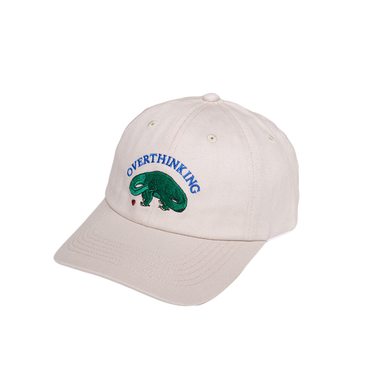 Beige cap with 'Overthinking' and a green dinosaur design on a white background