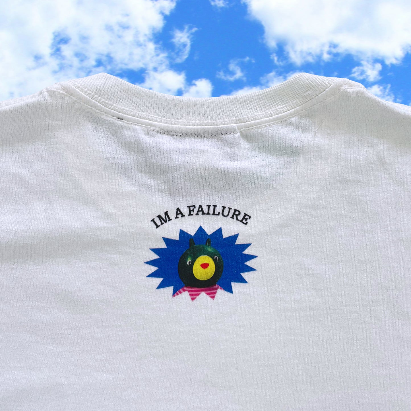 White t-shirt with a colorful graphic and 'I'm a Failure' text against a blue sky.