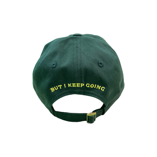 Green cap with 'BUT I KEEP GOING' text on a white background