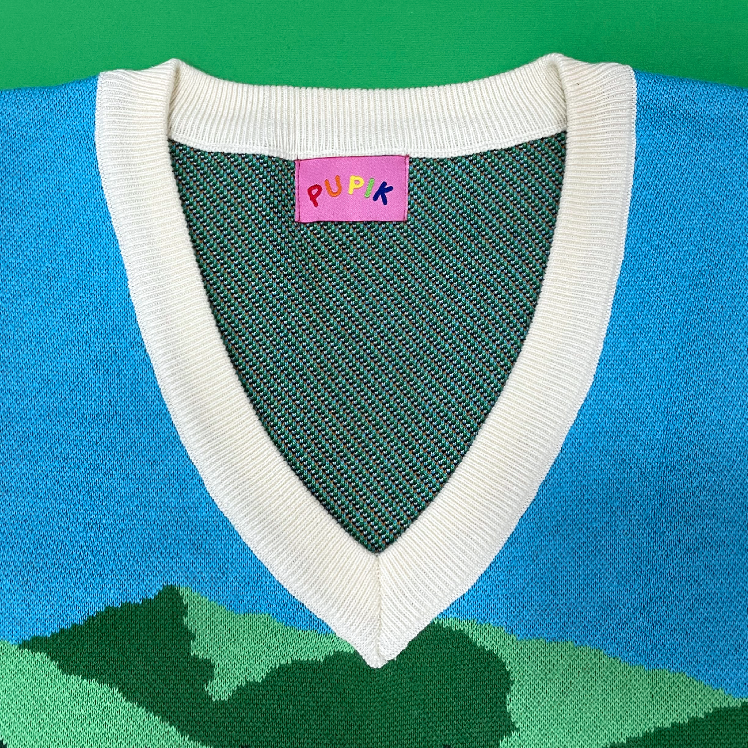 Close-up of a sweater with a visible brand label on a green background