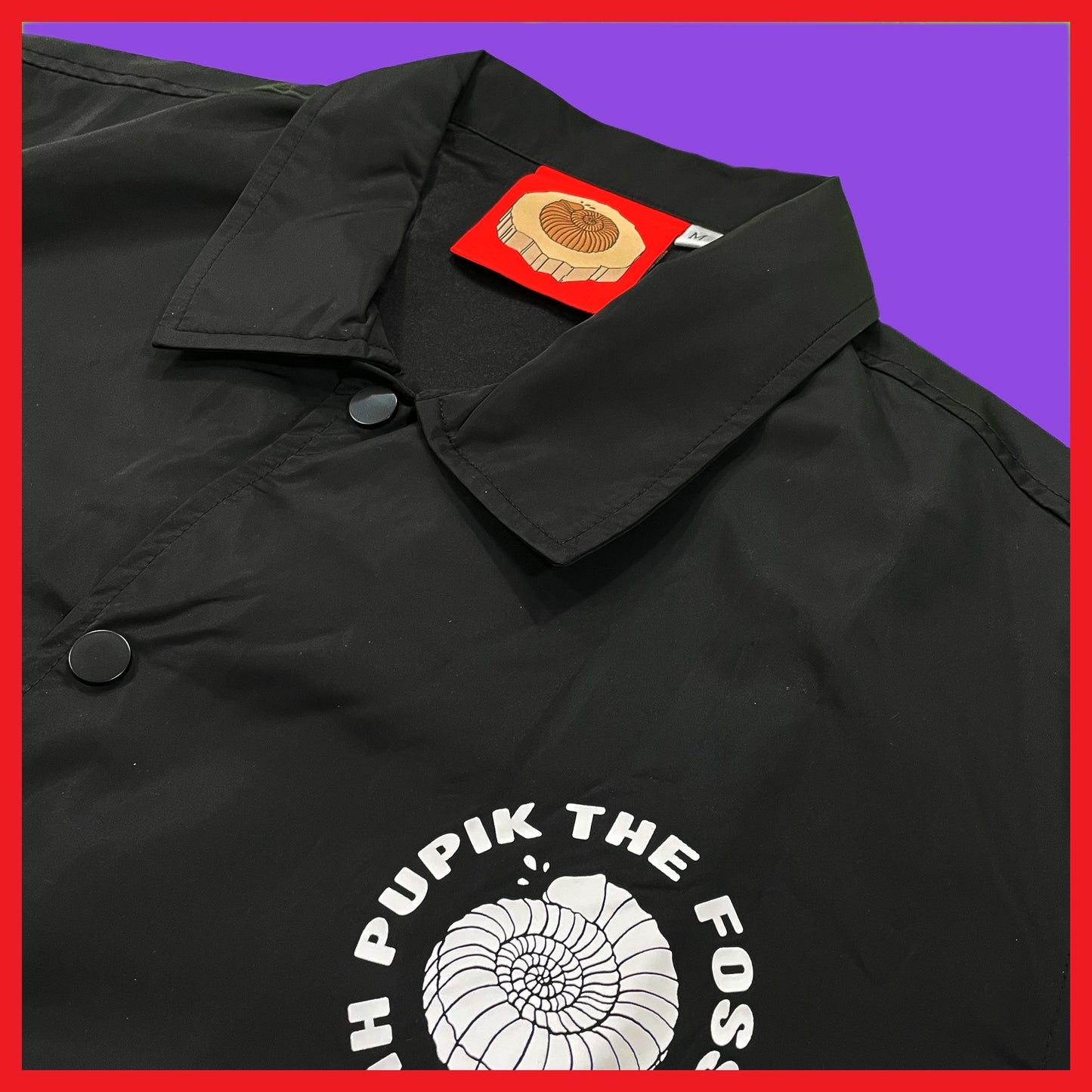 Close-up of Pupik The Fossil Hunter Windbreaker front logo and collar with red custom tag